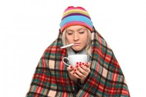 Ill woman covered with blanket holding a tea cup